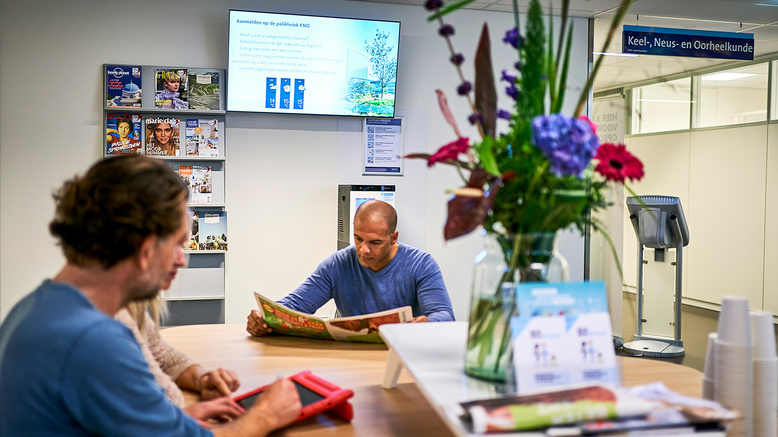 Patienten zitten met tablet in wachtkamer